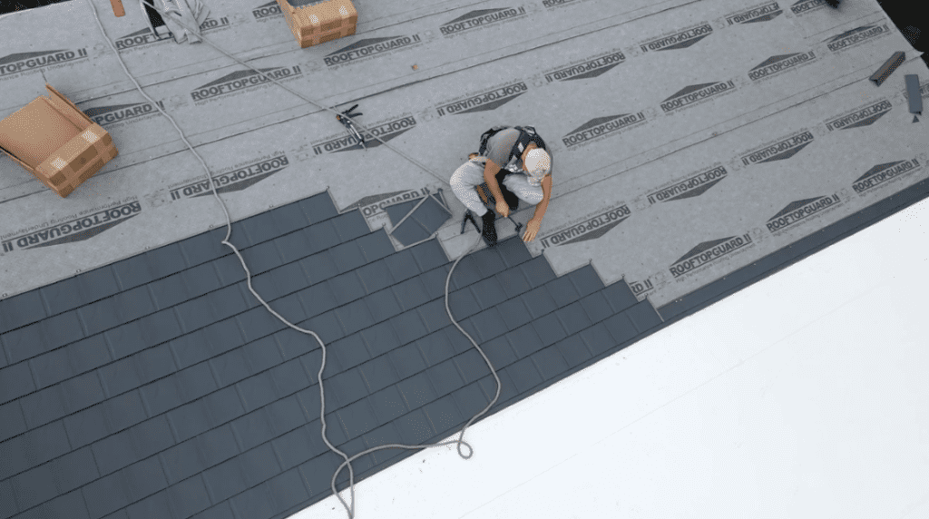 Mountaintop Metal Roofing crew member installing metal shingles on a home. Picture taken from above the home.